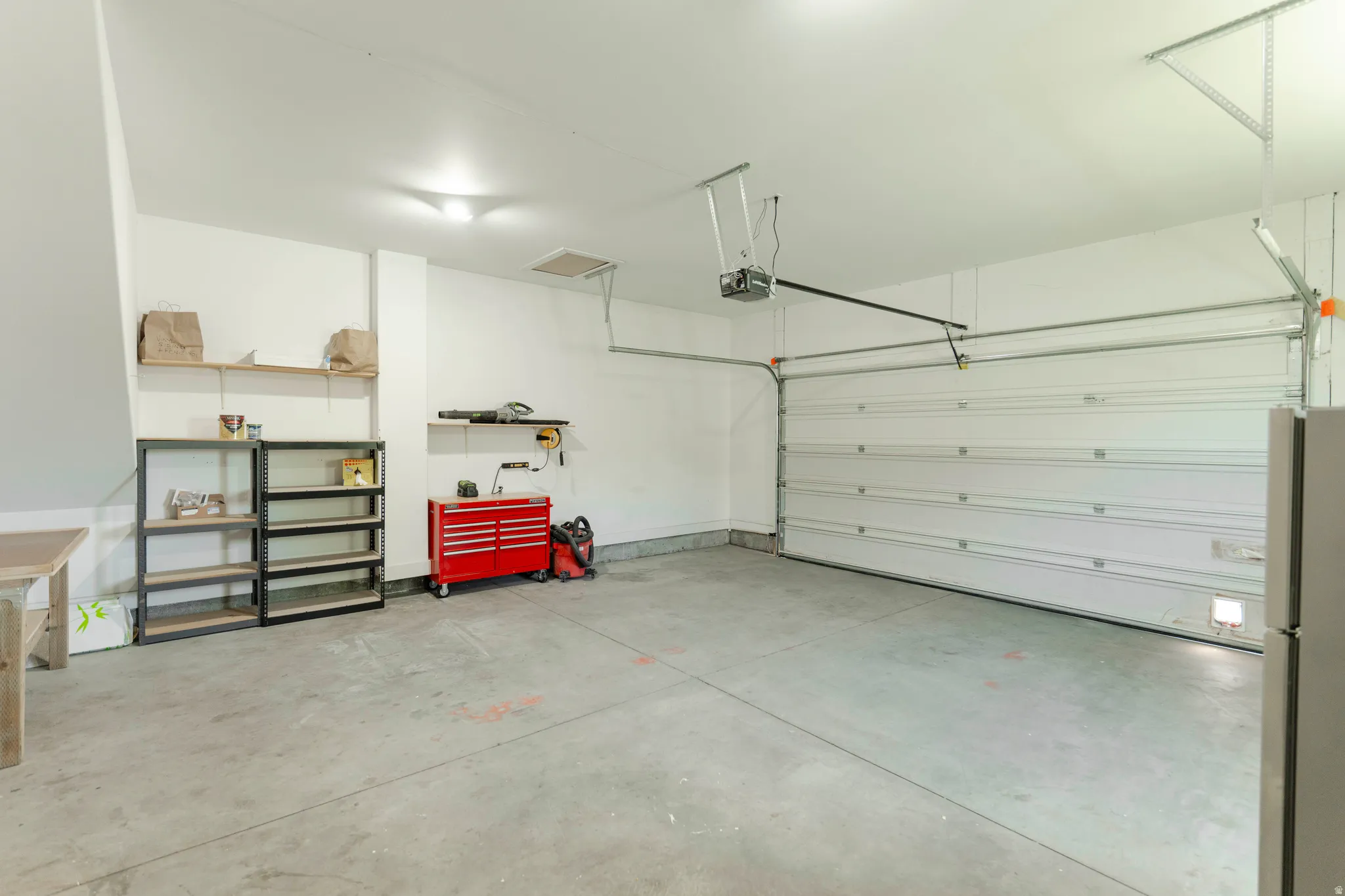 Spacious garage featuring a large overhead door, concrete flooring, and multiple built-in shelving units for organized storage