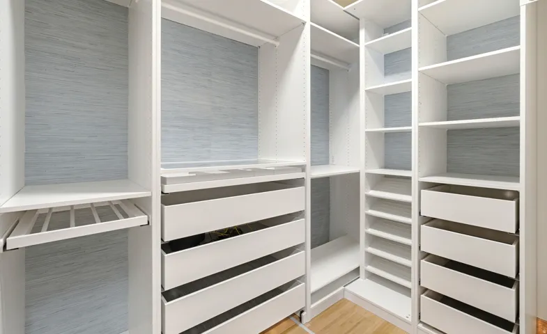 Custom closet system featuring pants hanger rack, shoe racks, jewelry drawer, valet hook, suitcase nook, and ironing board nook.