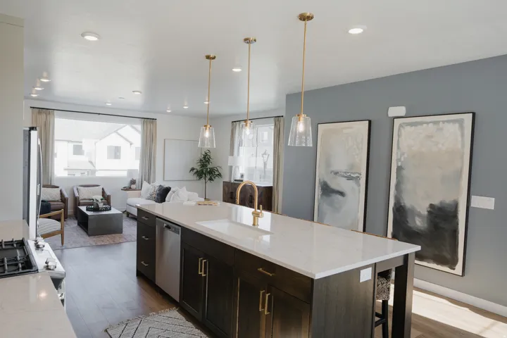 Spacious kitchen island with a white countertop and dark cabinetry, featuring a built-in sink with a brass-finish faucet