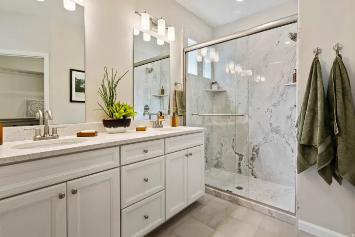Dual sink vanity with white cabinetry and light-colored countertops
