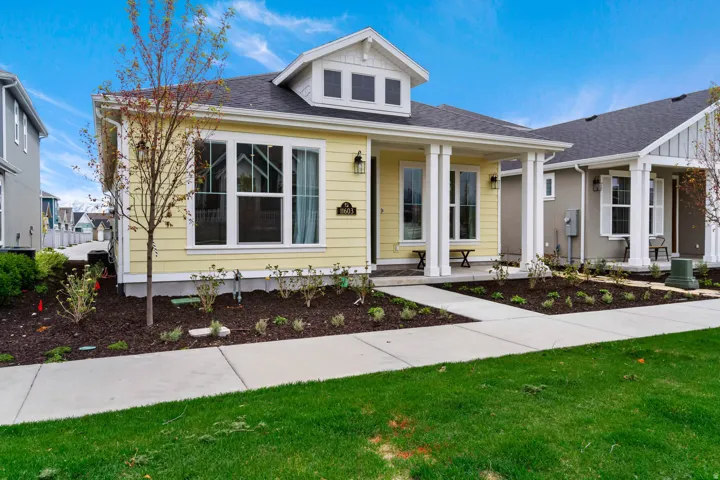 Yellow siding exterior with white trim, featuring a covered front porch with white columns