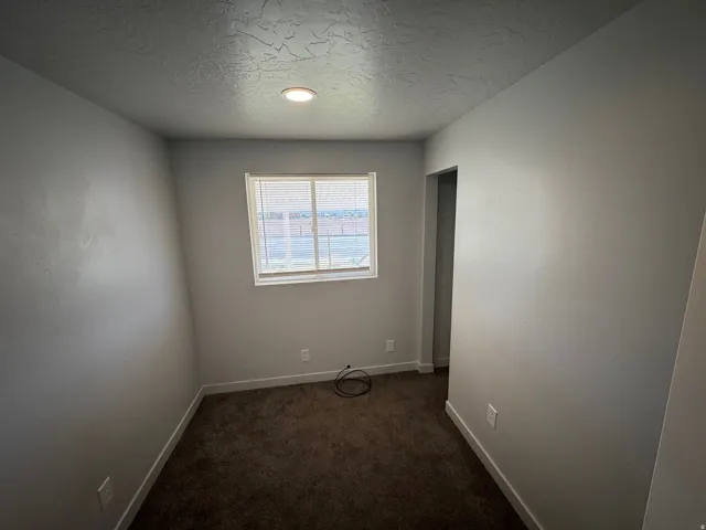 Room featuring neutral-toned walls, recessed lighting, and a single window with horizontal blinds