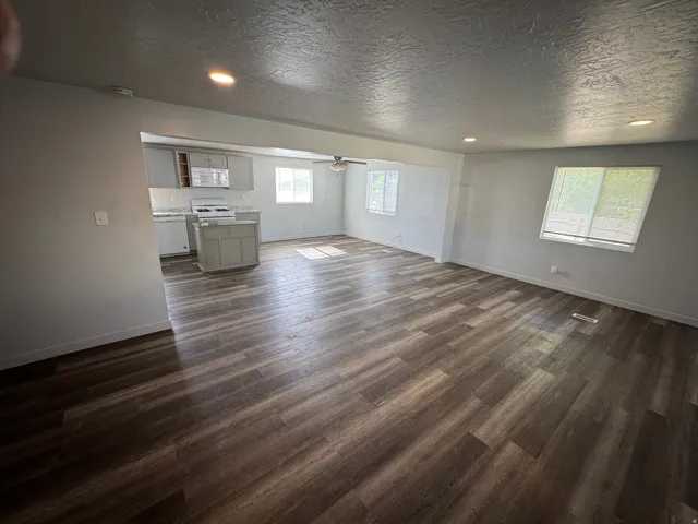 Open-concept living area featuring wood-finish flooring, recessed lighting, and ample natural light from multiple windows