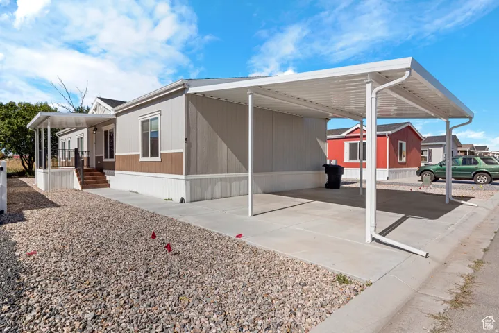 Two-tone exterior with light gray and brown siding, white window trim, and white foundation skirting