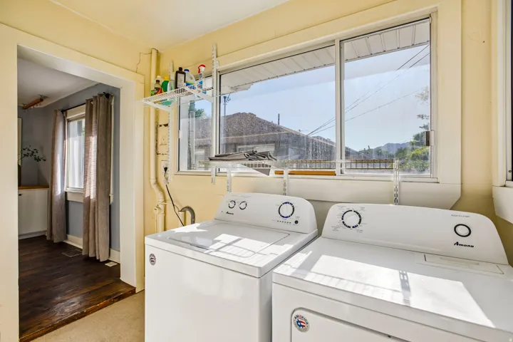 Dedicated laundry area with a large window, integrated shelving, and a hard surface flooring transition