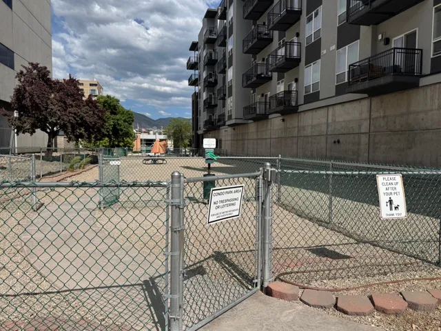 Community pet park featuring a chain-link fence, a gravel surface, and a dispenser station