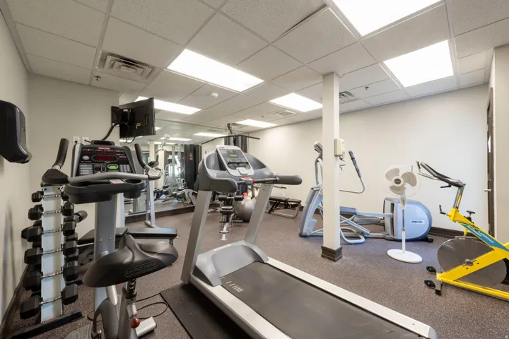 Fitness center featuring multiple exercise machines, mirrored wall, recessed lighting, and resilient flooring