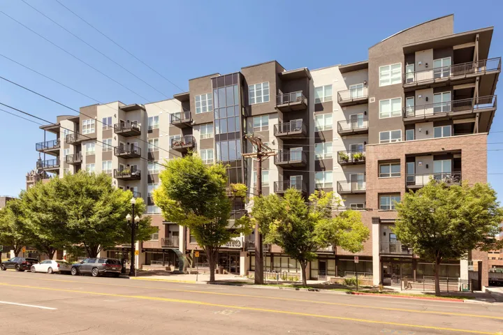 Contemporary multi-story building featuring a facade of varying materials including brick, stucco, and large glass panels