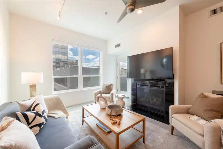 Living space featuring large windows, a built-in fireplace with a black surround, and track lighting