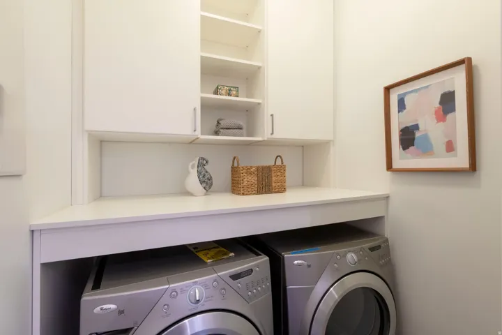Laundry area featuring white cabinetry, integrated shelving, and a built-in counter