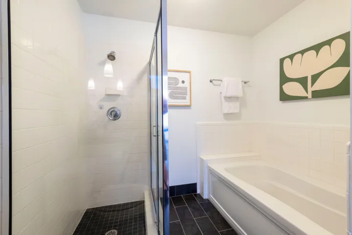 Full bathroom featuring a walk-in shower with white subway tile and a glass enclosure, alongside a built-in bathtub with a white tiled surround