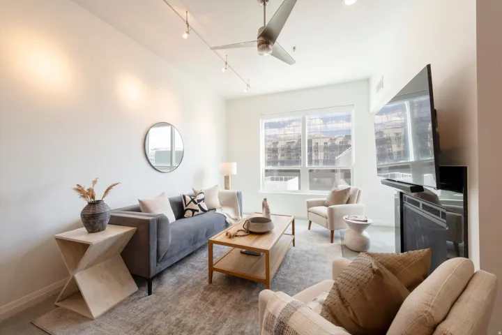 Bright living area featuring a modern ceiling fan, track lighting, and a wide window