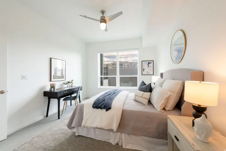 Spacious room with large windows, light gray carpeting, and a ceiling fan with integrated lighting