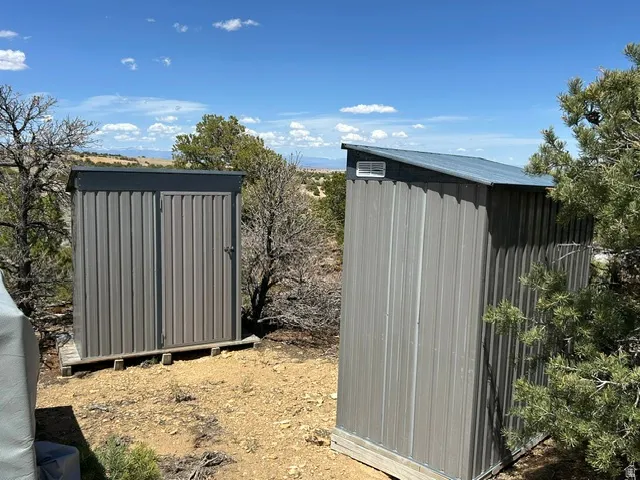 Two metal storage sheds with sloped roofs and louvered vents, situated on wood bases