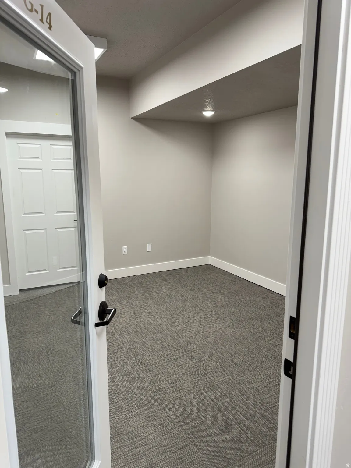 Room featuring light gray walls, gray patterned carpet, white baseboards, and overhead recessed lighting