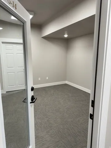 Room featuring light gray walls, gray patterned carpet, white baseboards, and overhead recessed lighting
