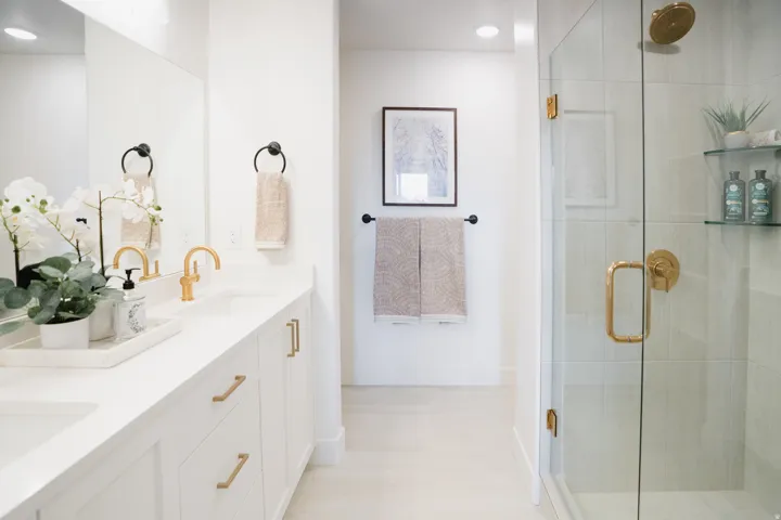 Dual vanity with white cabinetry, gold-tone hardware, and white countertops