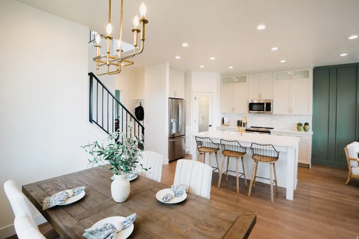 Open-concept dining area featuring wood-finish flooring, a contemporary chandelier, and a dark wood dining table