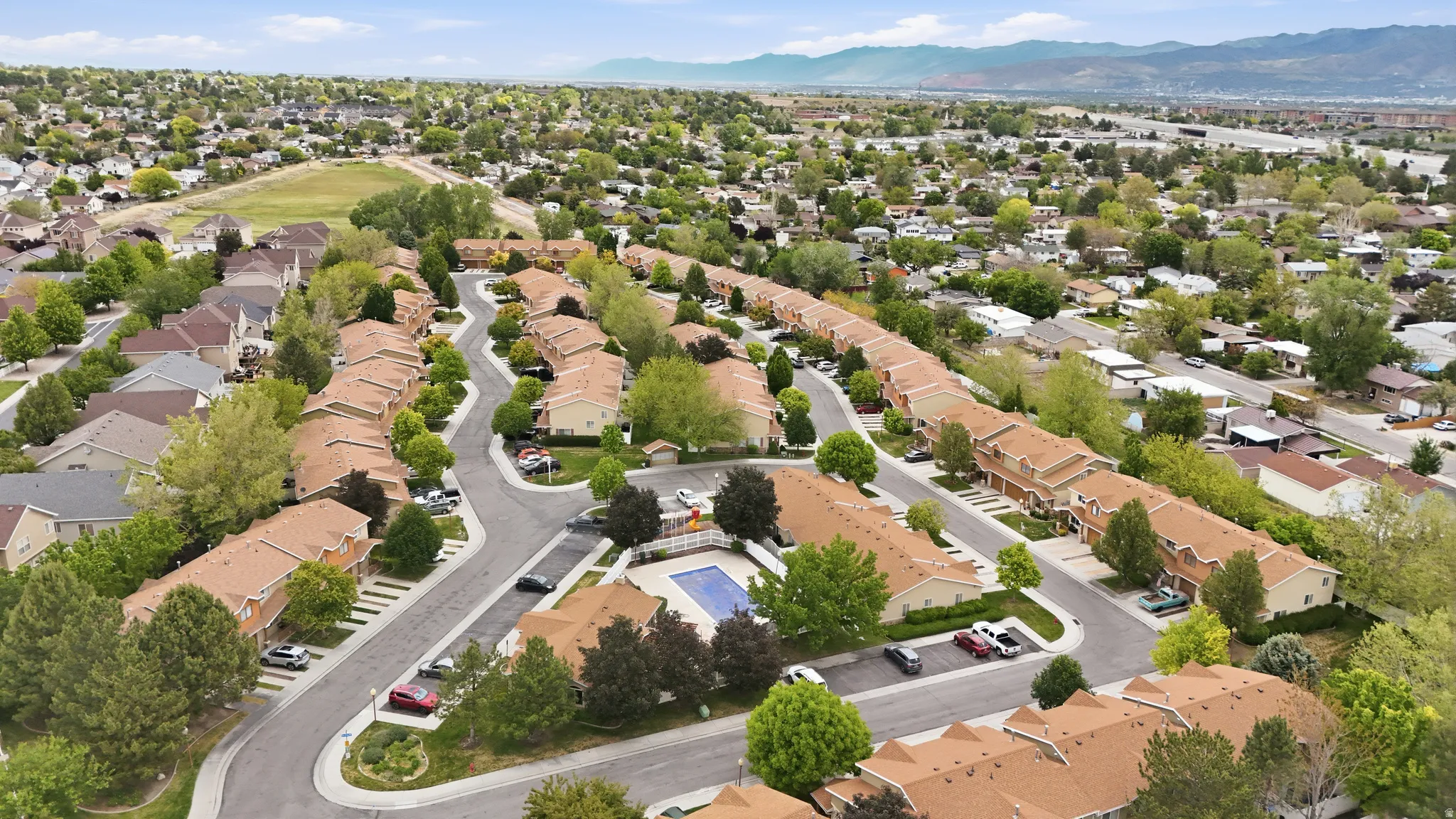 Aerial overview of a residential community featuring multiple two-story townhome buildings with light brown shingle roofs