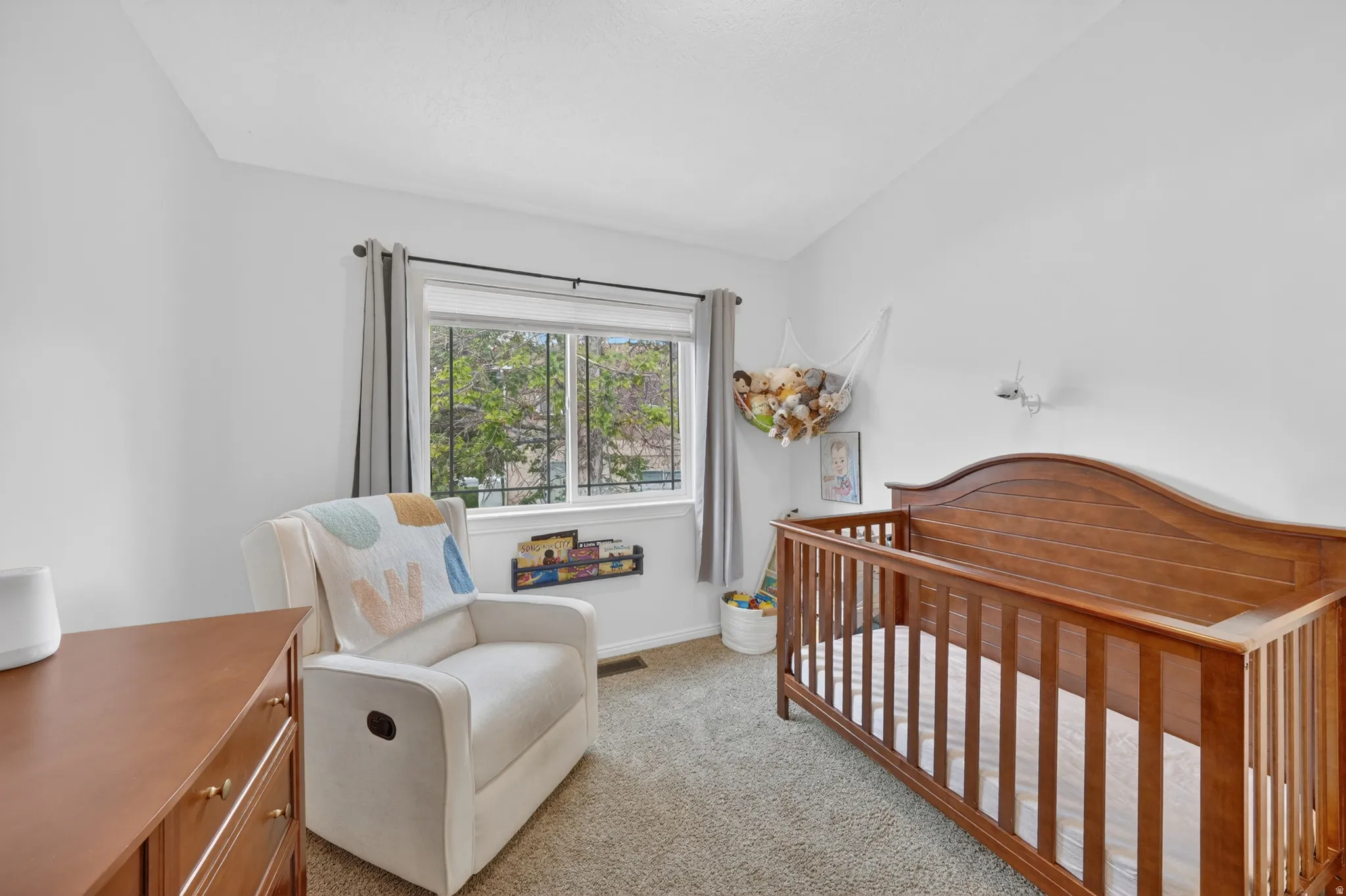 Carpeted room featuring a white wall finish, a window with grey drapes, and a built-in wall shelf
