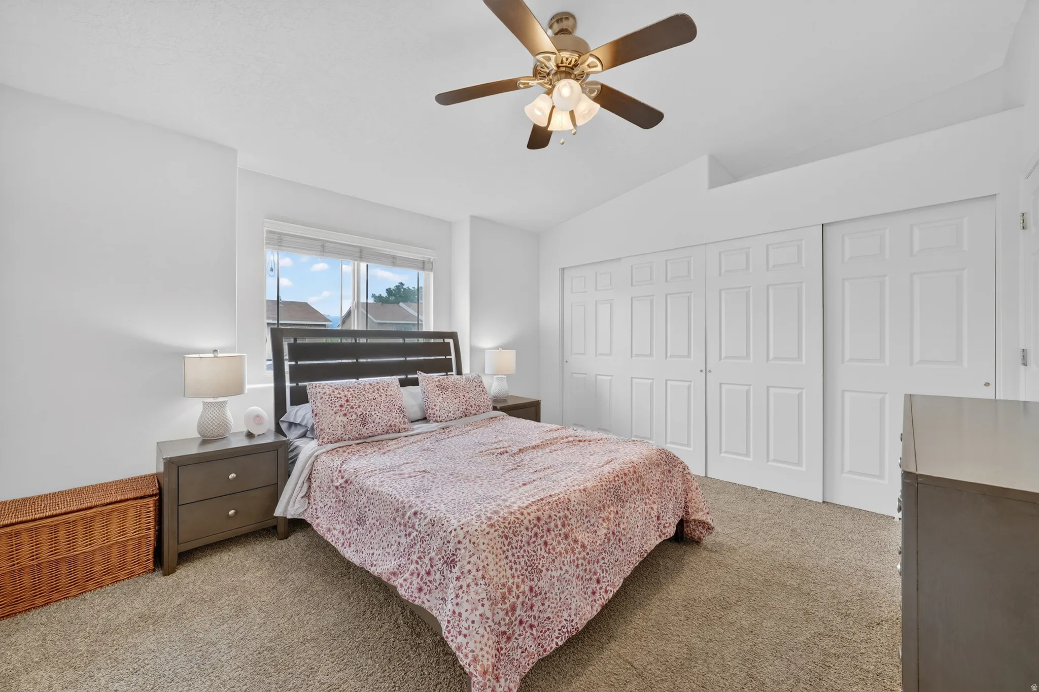 Bedroom featuring a large window, neutral carpeting, and a ceiling fan with integrated lighting