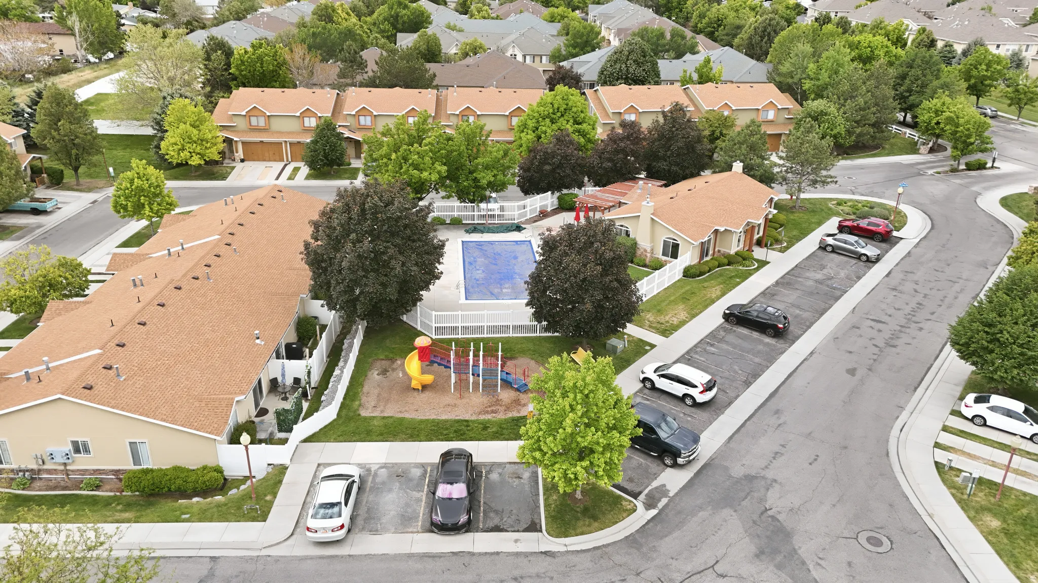 Aerial perspective showcasing multiple properties, a community pool, and a playground