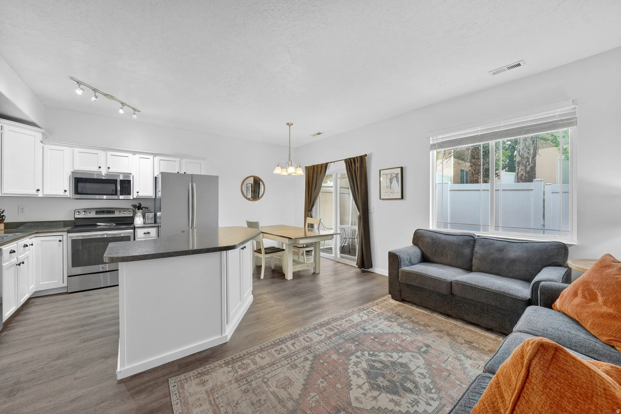 Open-concept living area featuring a kitchen island with dark countertops, white cabinetry, and stainless steel appliances