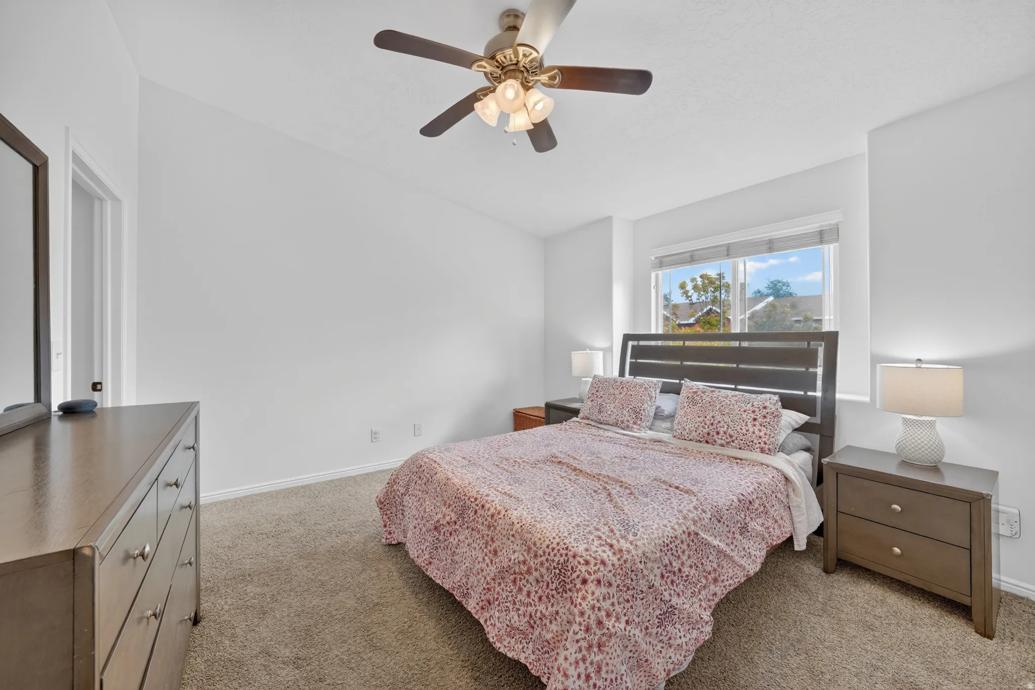 Carpeted room featuring a ceiling fan with integrated lighting, a window with blinds, and white walls