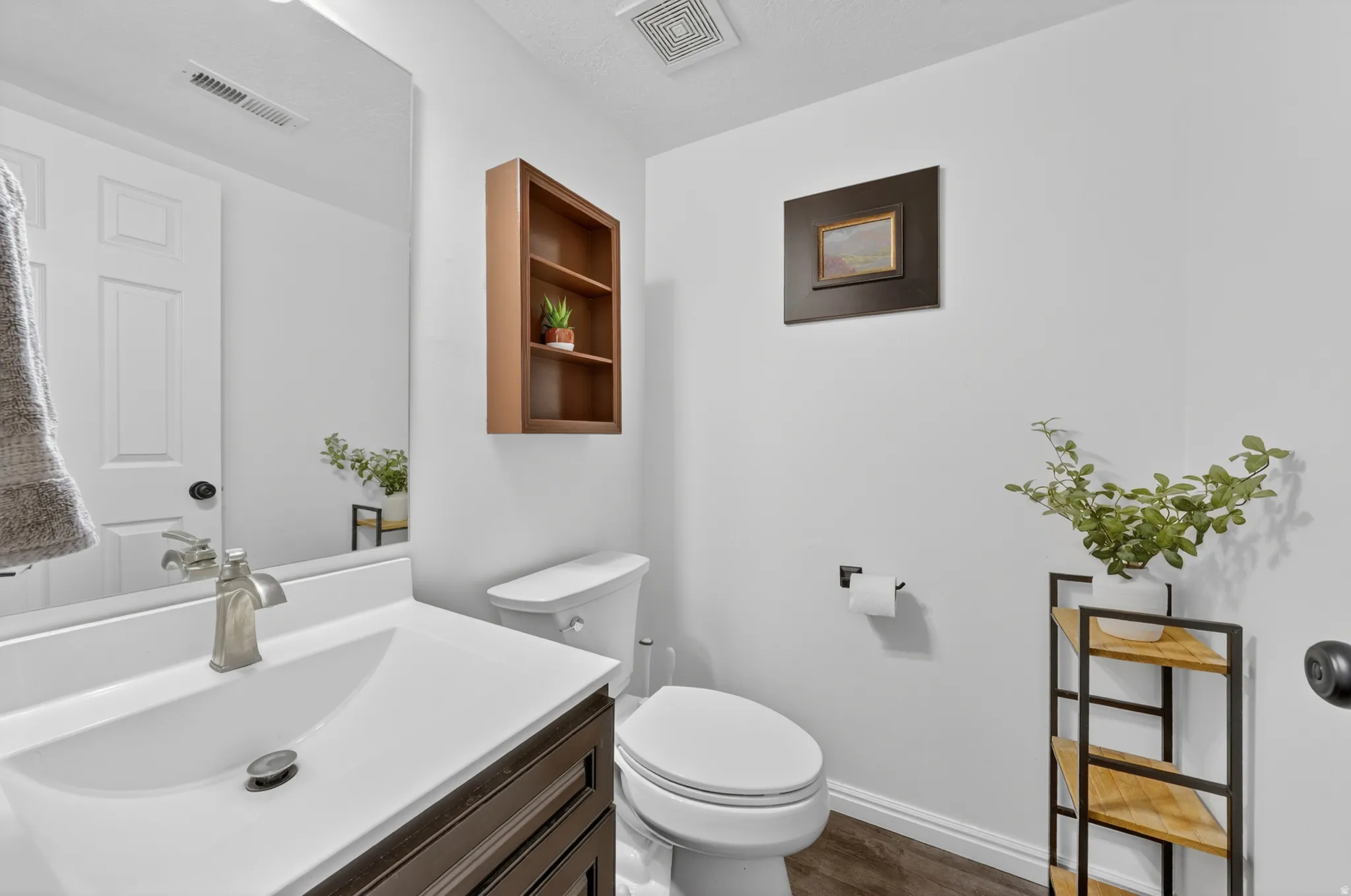 Vanity featuring a white countertop and undermount sink, brushed nickel faucet, and dark wood-finish cabinetry