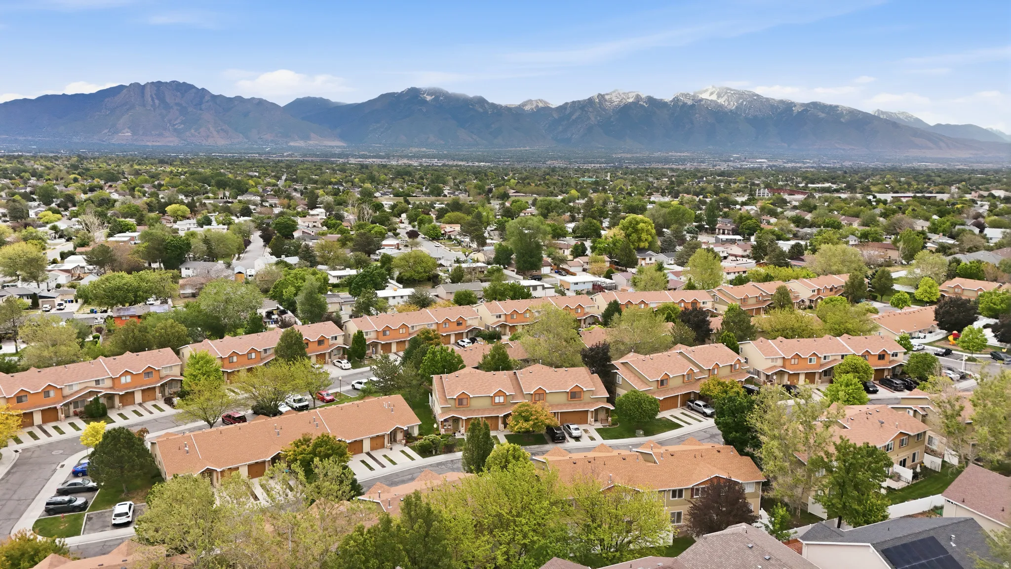 Aerial perspective showcasing a residential community with abundant mature trees and distant mountain ranges