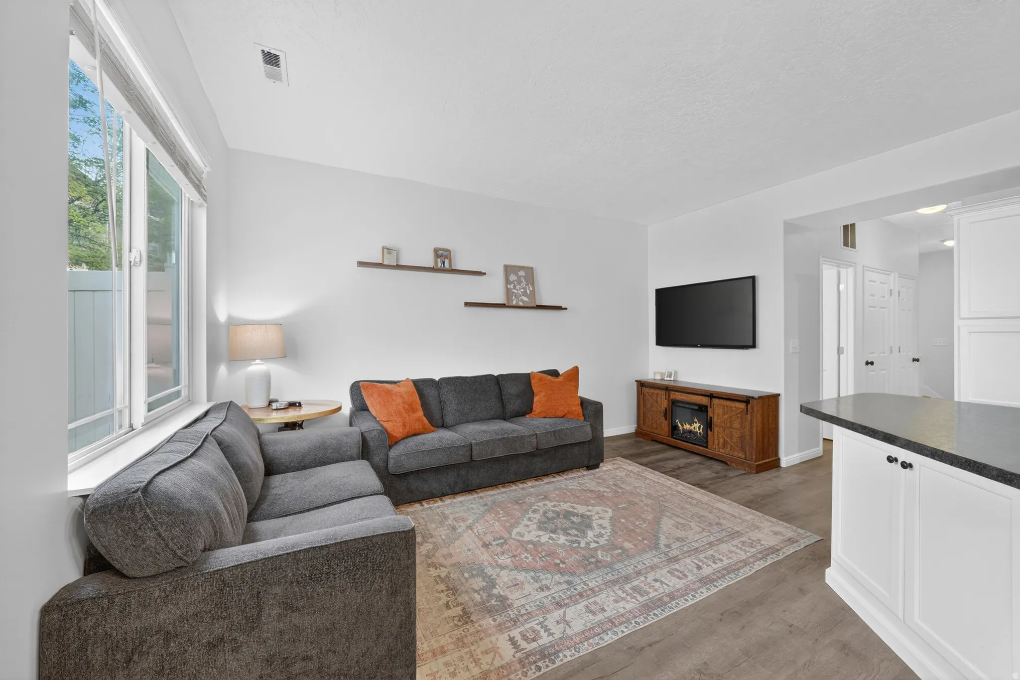 Living room featuring wood-finish flooring, white walls, and a large window