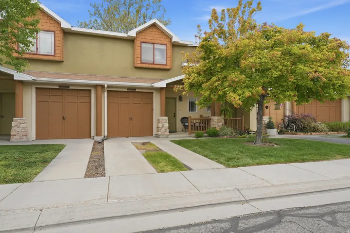 Townhome exterior with a light stucco finish and contrasting brown garage doors