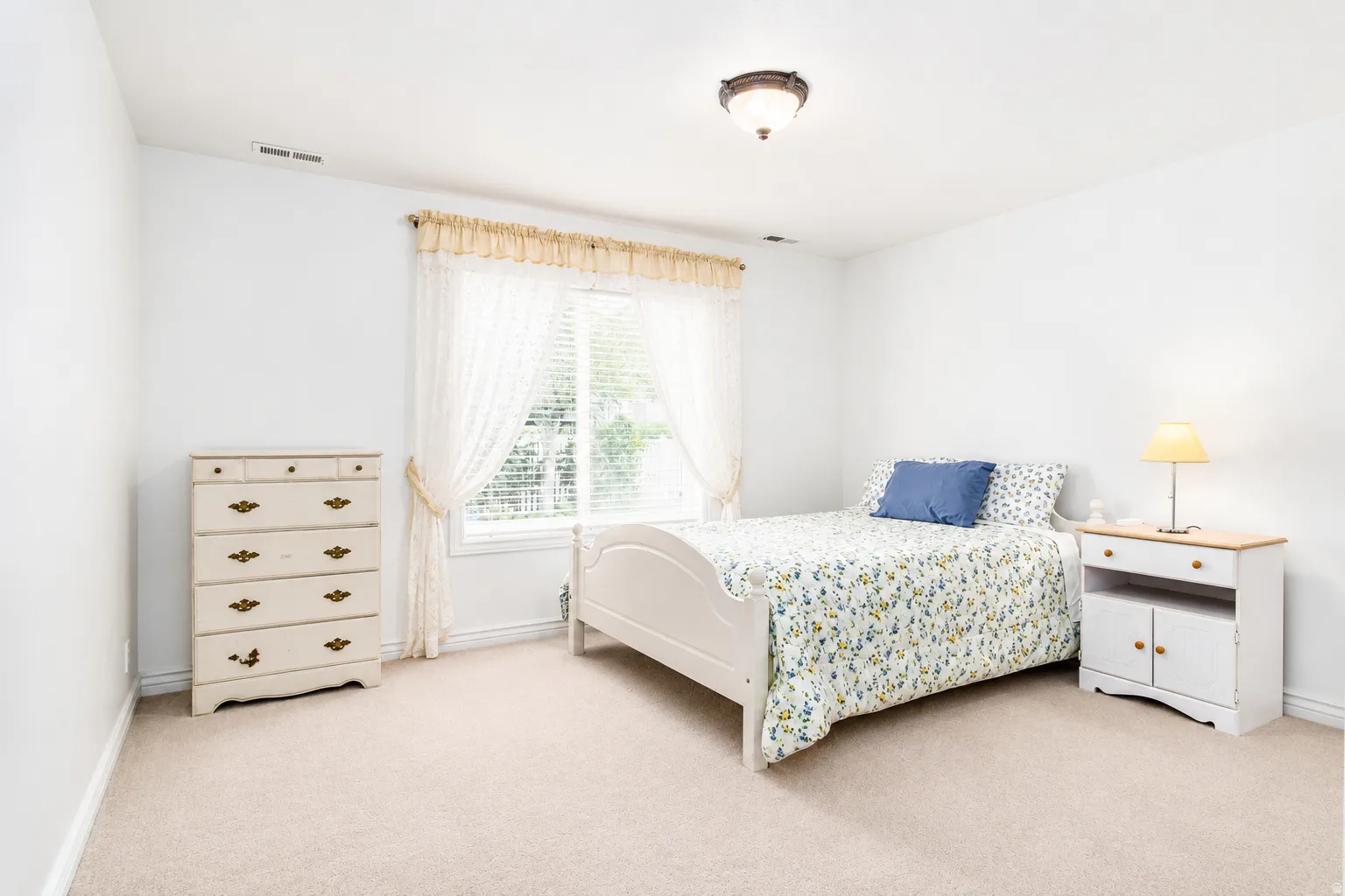 Bright bedroom with neutral wall paint and plush carpet flooring