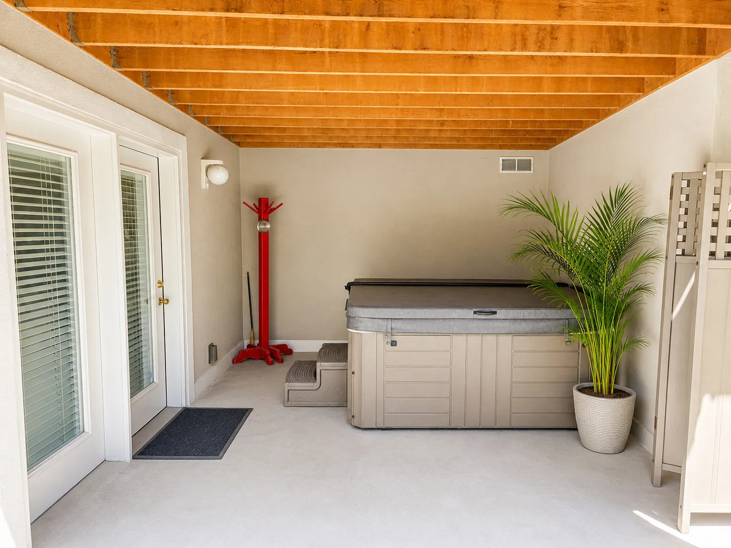 Covered patio with a spa, exposed wood ceiling beams, concrete flooring, and double French doors