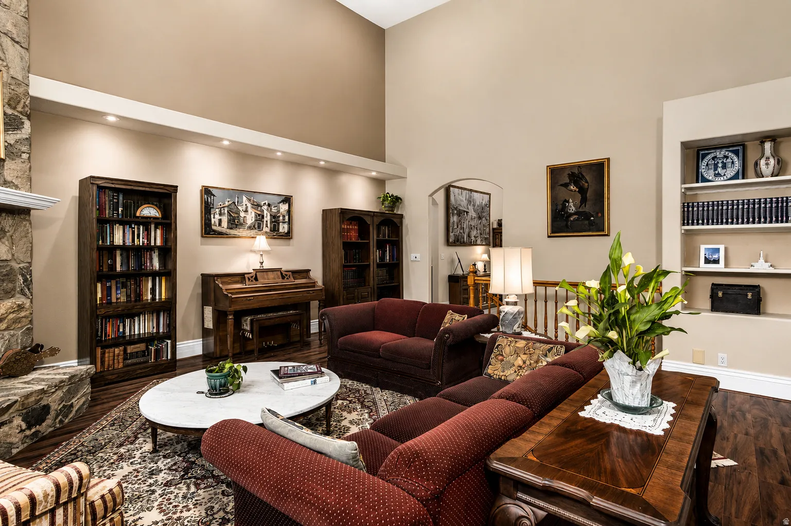 Spacious living area featuring a stone fireplace with a substantial hearth and mantel, high vaulted ceilings, recessed lighting, and rich wood-finish flooring
