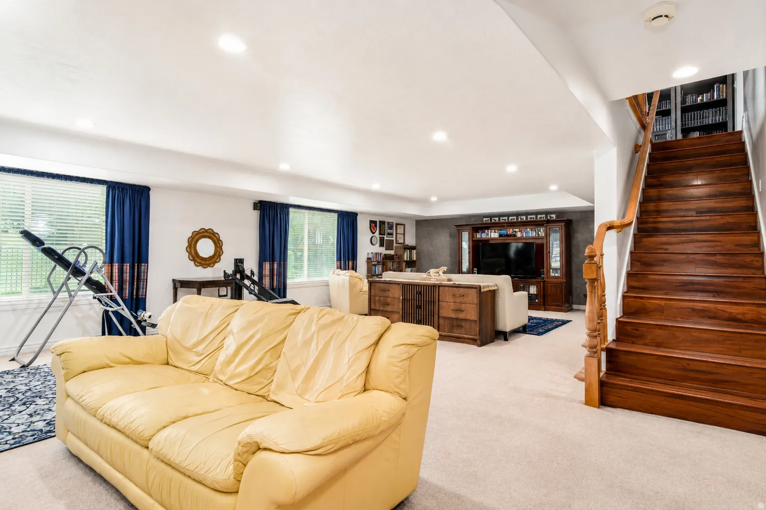 Finished lower level featuring recessed lighting, carpet flooring, a built-in media center, and a wood staircase with a matching railing