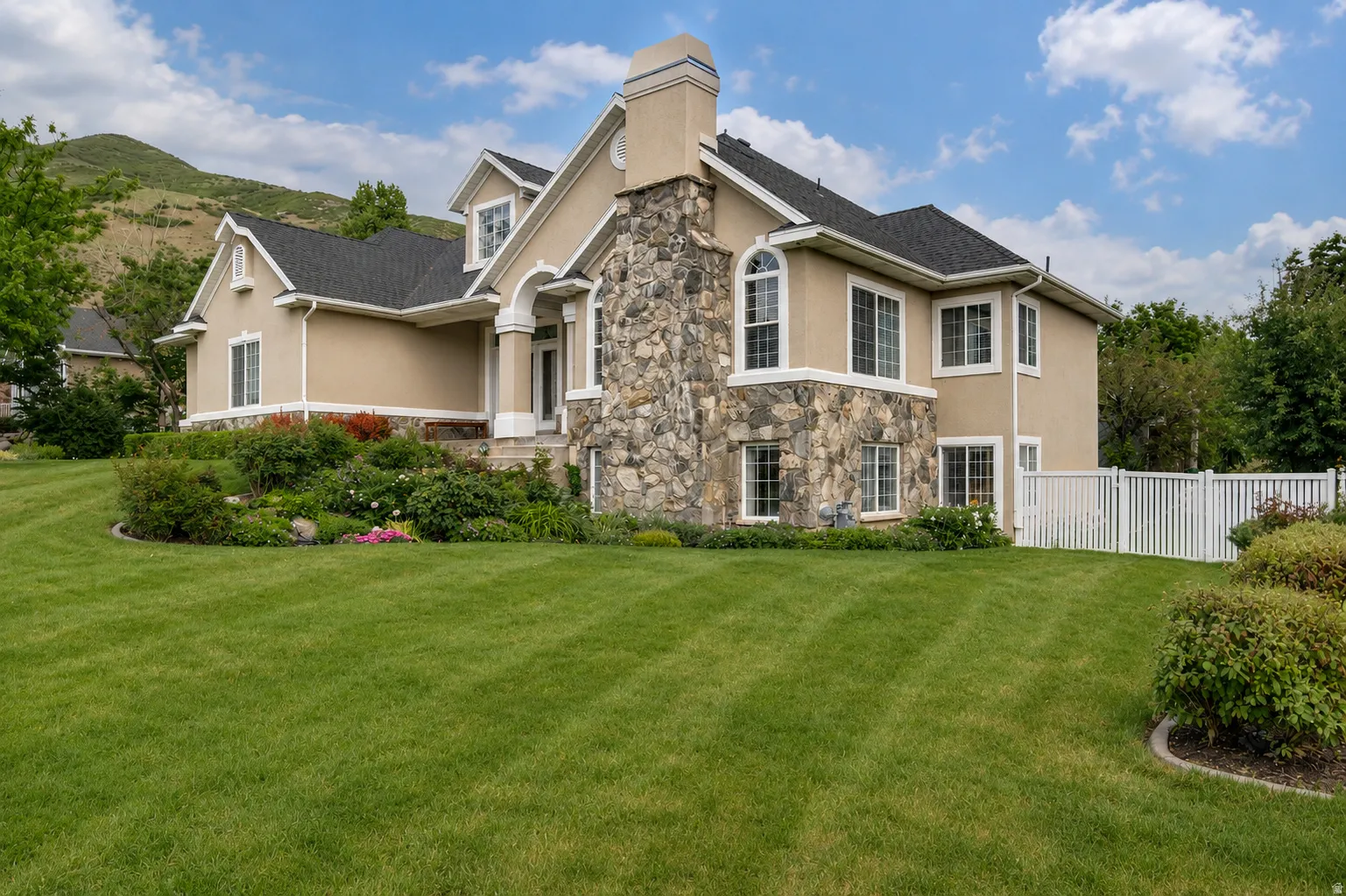 Stucco exterior with stone accents, a multi-gabled roof, and white window trim