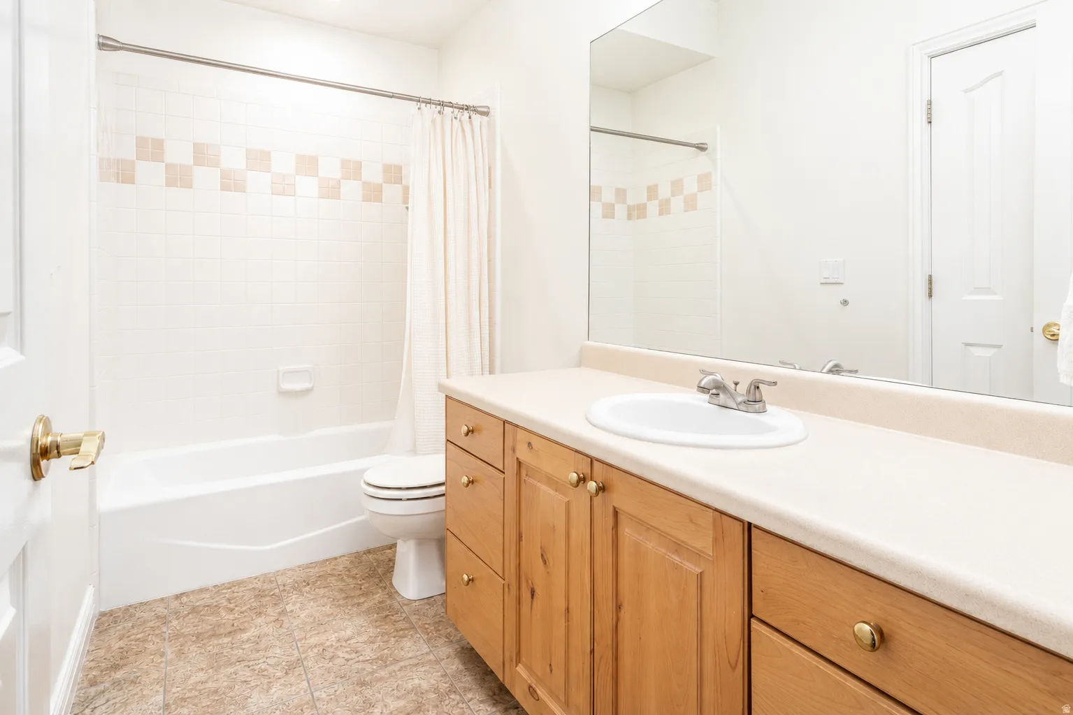 Bathroom featuring a full-width vanity with wood-finish cabinetry, an integrated sink, and a large wall-mounted mirror