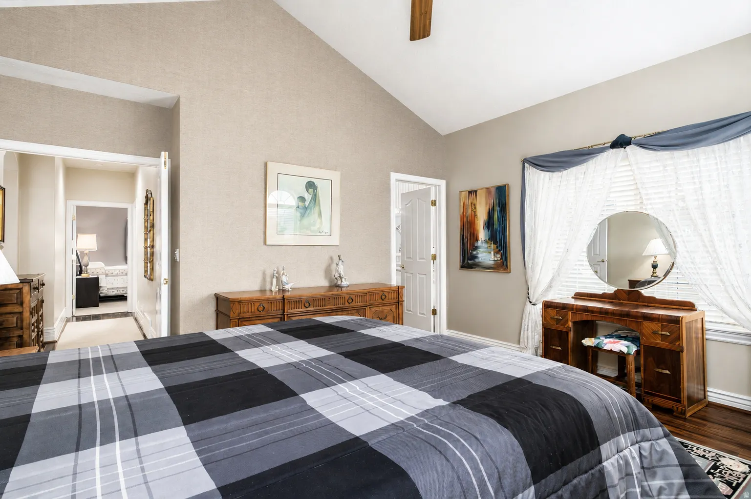 Vaulted ceiling bedroom with ceiling fan, wood-finish flooring, and natural light from a window with blinds