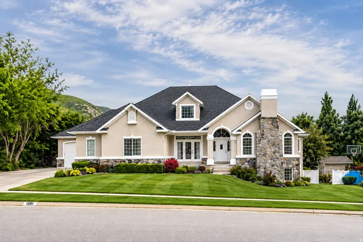 Stucco exterior featuring a stone accent chimney and foundation