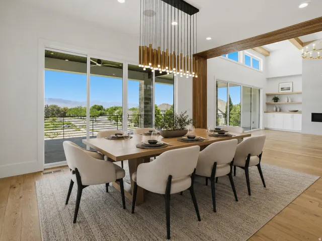 Spacious dining area featuring an expansive sliding glass door, contemporary linear chandelier, light wood-finish flooring, and a large wooden dining table AI Decor