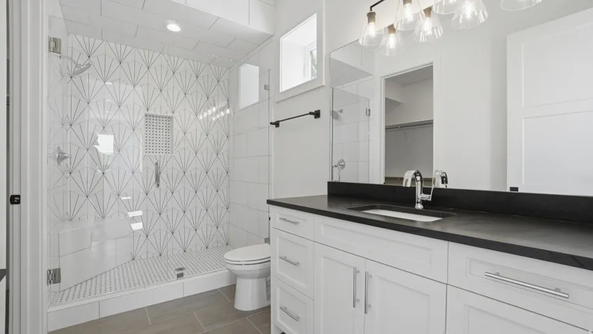 Contemporary bathroom featuring a spacious glass-enclosed shower with a decorative tiled accent wall and built-in niche