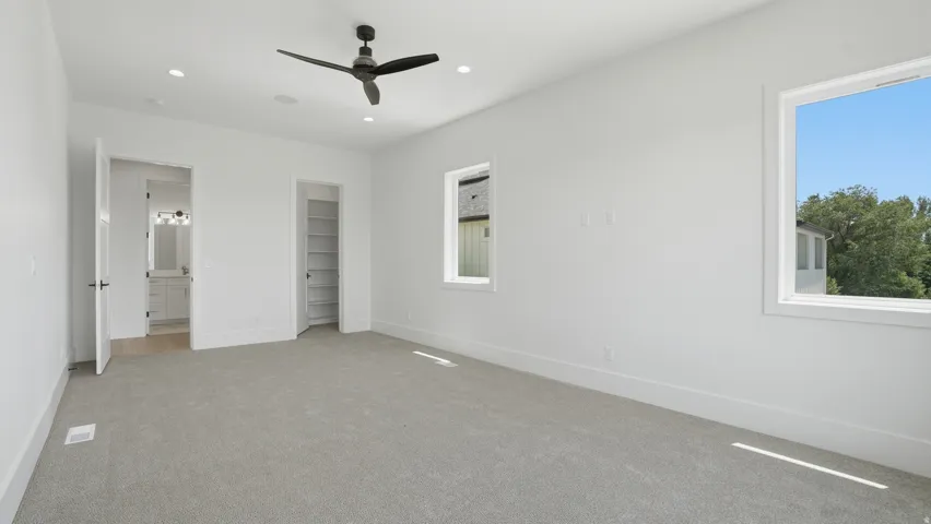 Spacious room featuring light-toned carpeting, white walls, and two large windows