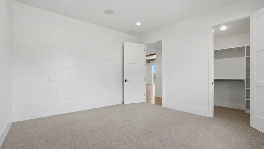 Spacious room featuring light-colored carpeting and a distinctive white accent wall with horizontal paneling