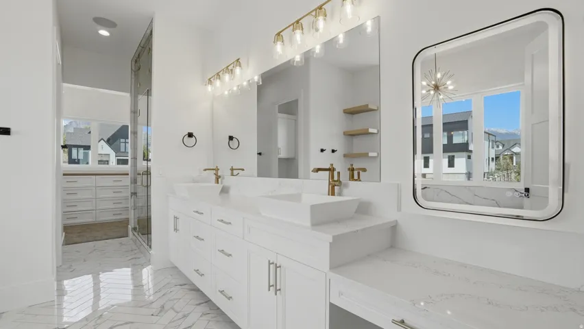 Double vanity with white cabinetry, quartz countertops, and gold-finish fixtures