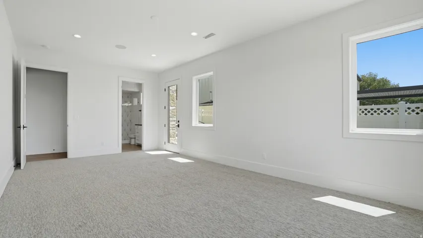 Spacious room with light-colored carpeting, white walls, and recessed lighting