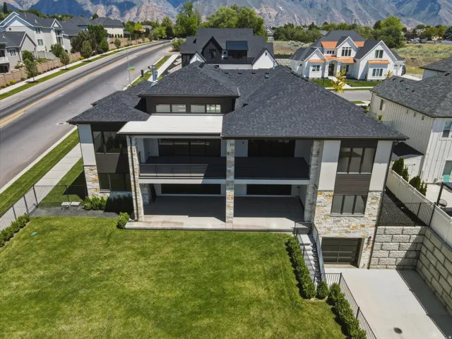 Contemporary multi-level residence featuring a dark shingle roof, stone and stucco facade, and multiple outdoor living areas