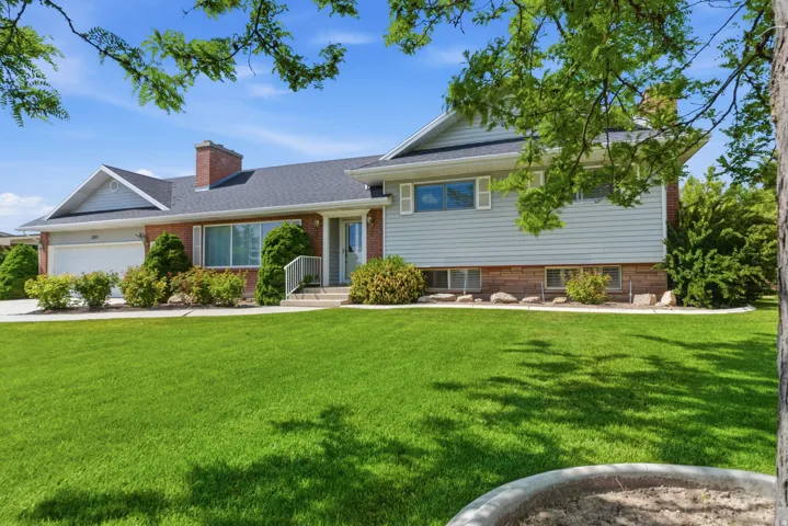 Split-level residence featuring a two-car garage, brick and siding exterior, and a dark shingle roof