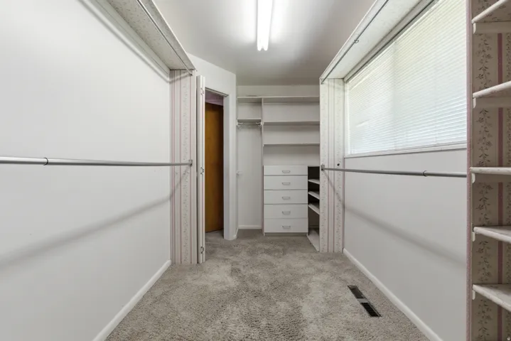 Spacious walk-in closet featuring built-in shelving, integrated drawers, and ample hanging rods