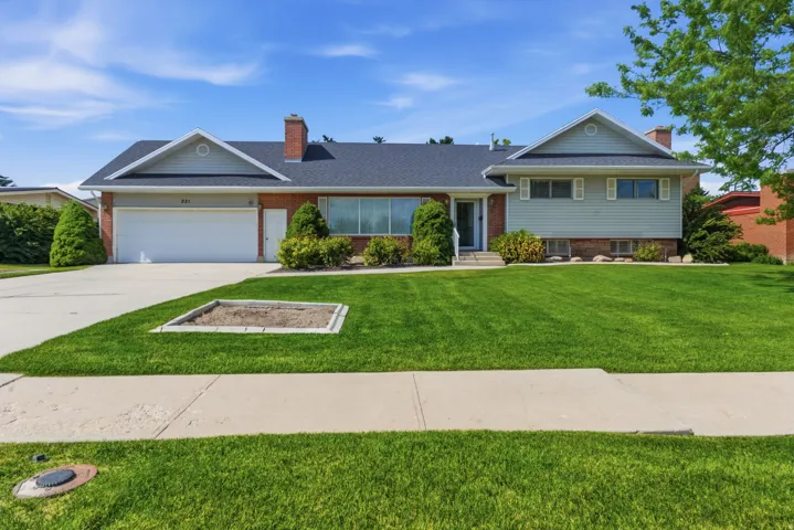 Traditional brick and siding exterior featuring a two-car garage, mature front lawn, and established landscaping